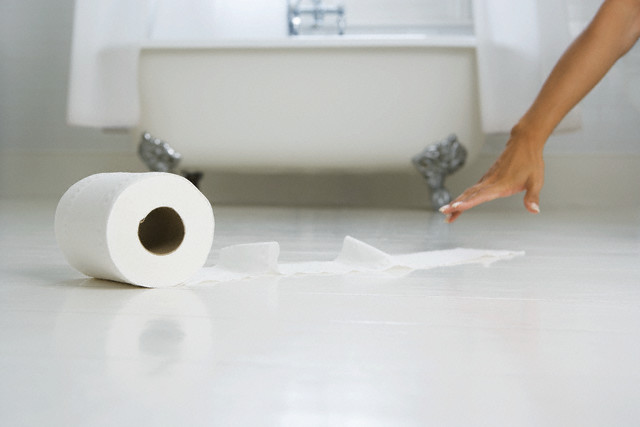 Woman Reaching for Toilet Paper Roll on the Floor